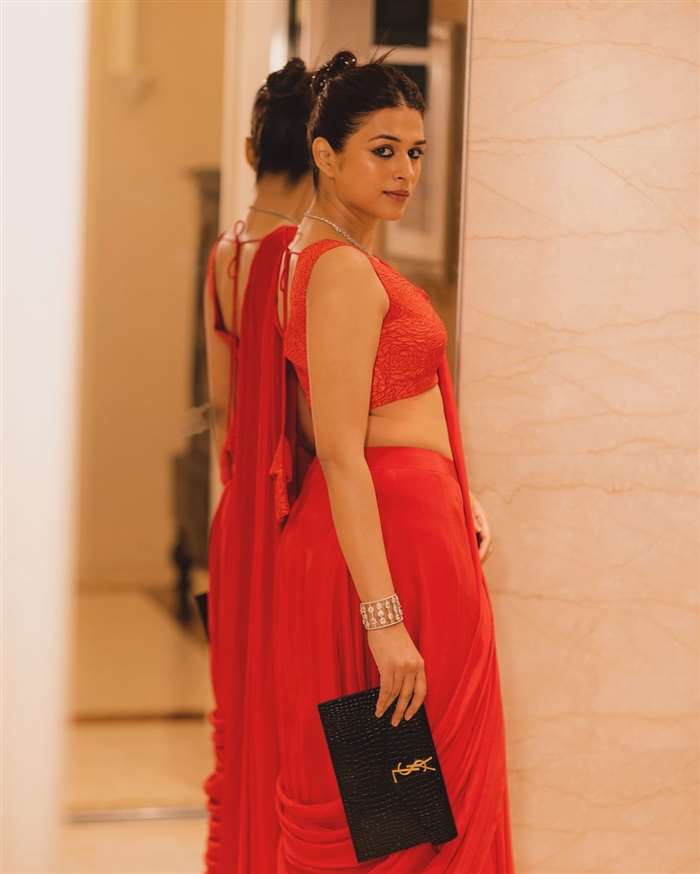 adding an element of allure to the outfit. Its fitted design complements the flowing saree,