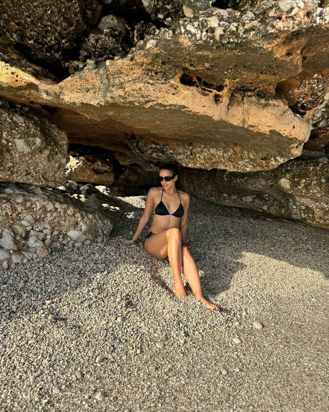 Tripti Dimri black bikini, paired with a sarong, hat, and sunglasses.