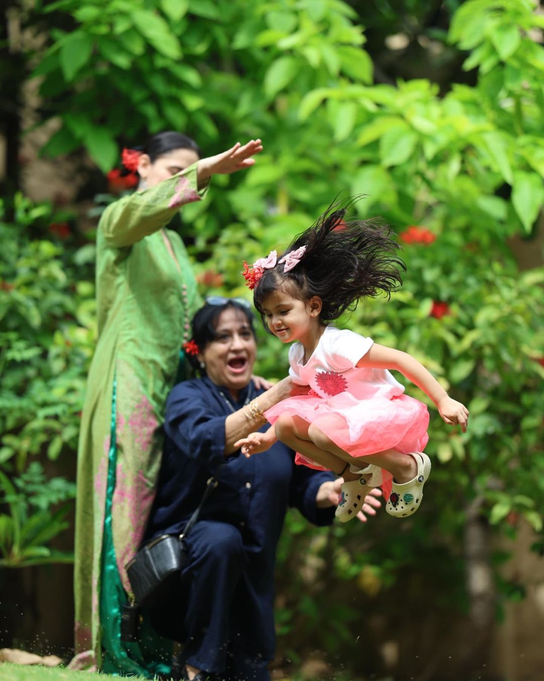 Ayra matched her mother's style in a white t-shirt, pink pleated skirt, grey crocs on her feet