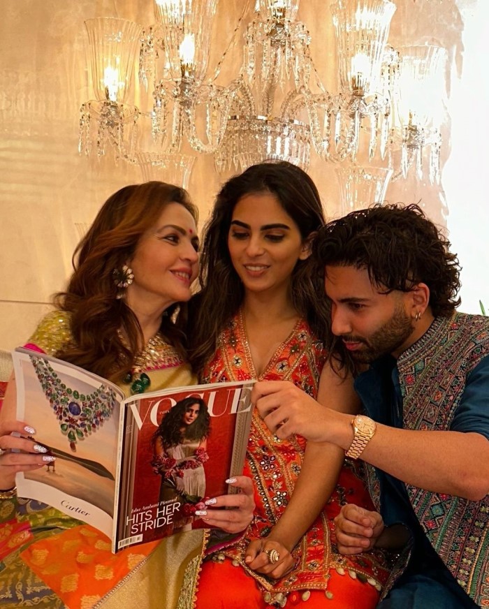 The image shows Nita holding the magazine while looking at Isha, with Orry peeking into the magazine from the side.