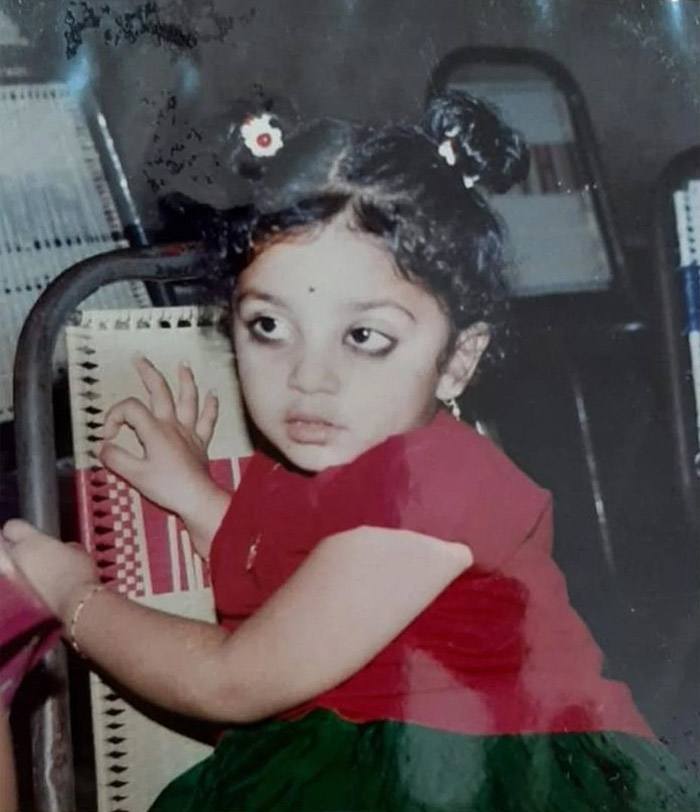She sports two cute ponytails tied with flower bands, adding to her charming look