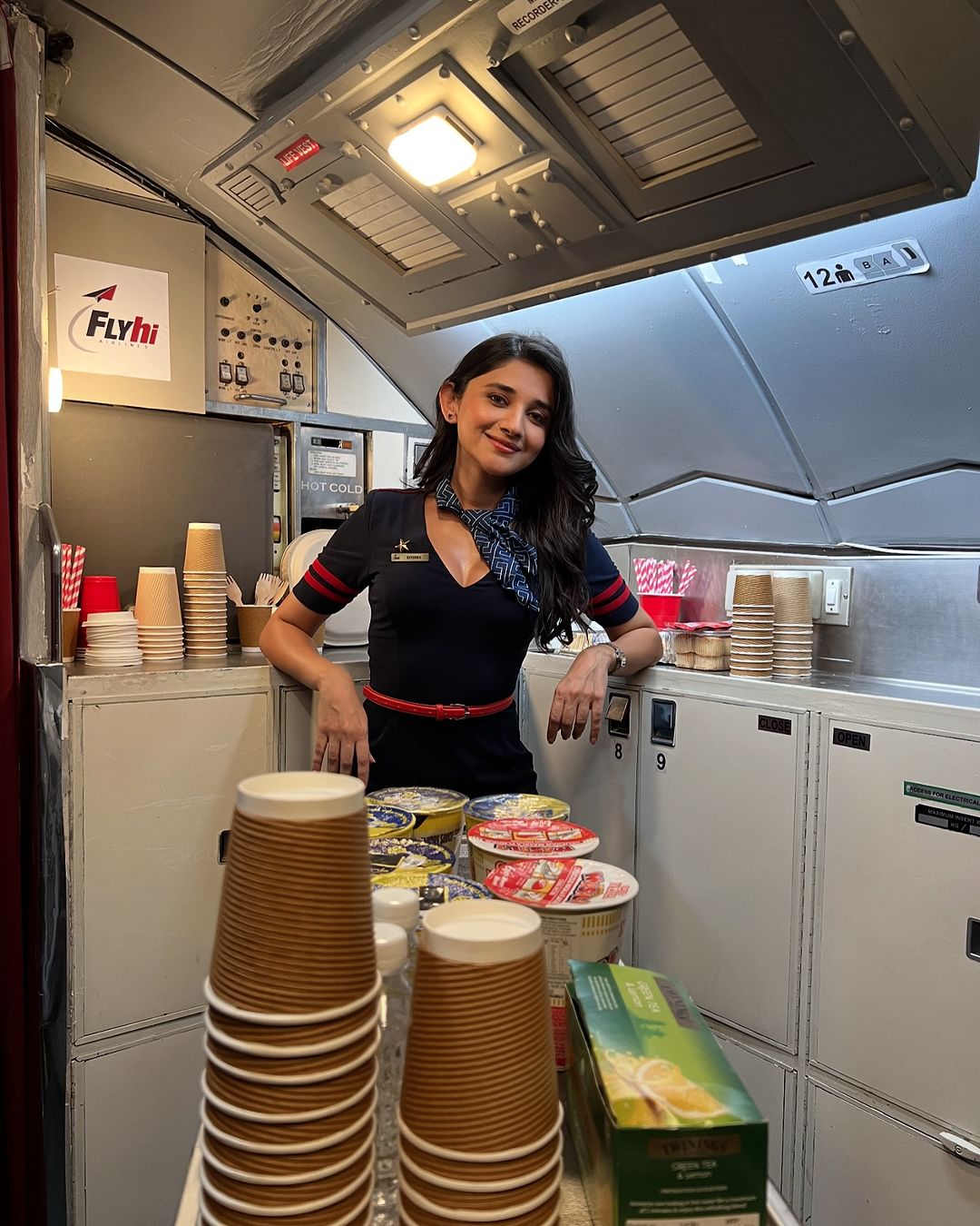 Kanika Mann is seen wearing a classic flight attendant uniform, complete with a blazer, skirt.