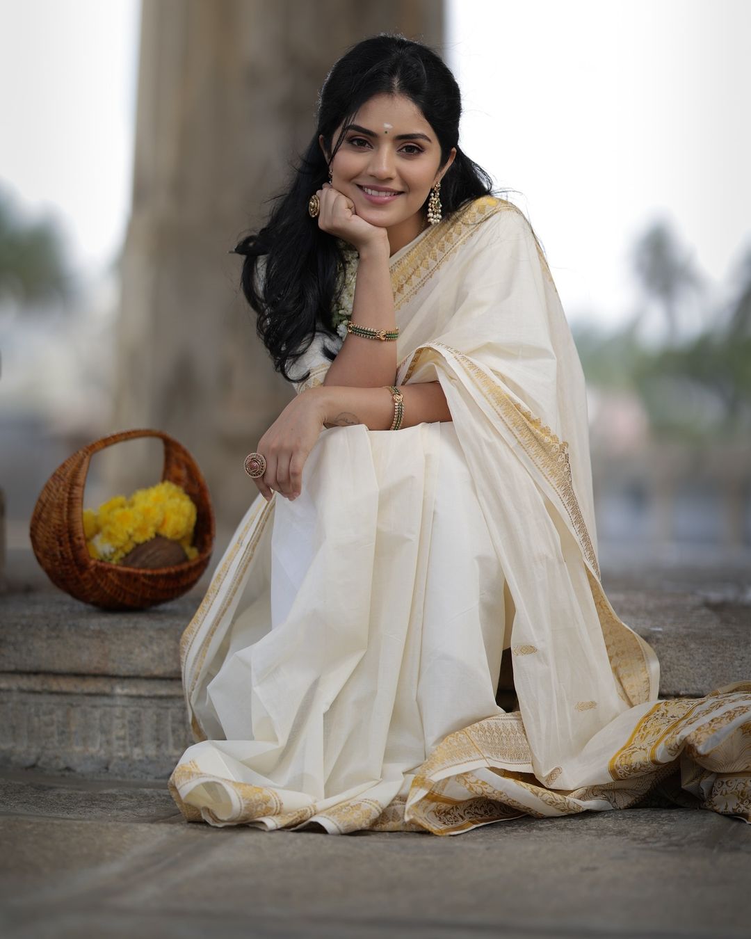 Megha Shetty is seen wearing a beautiful cream-colored saree with a gold border.