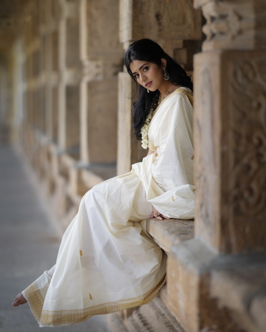 Megha Shetty is seen wearing a beautiful cream-colored saree with a gold border.