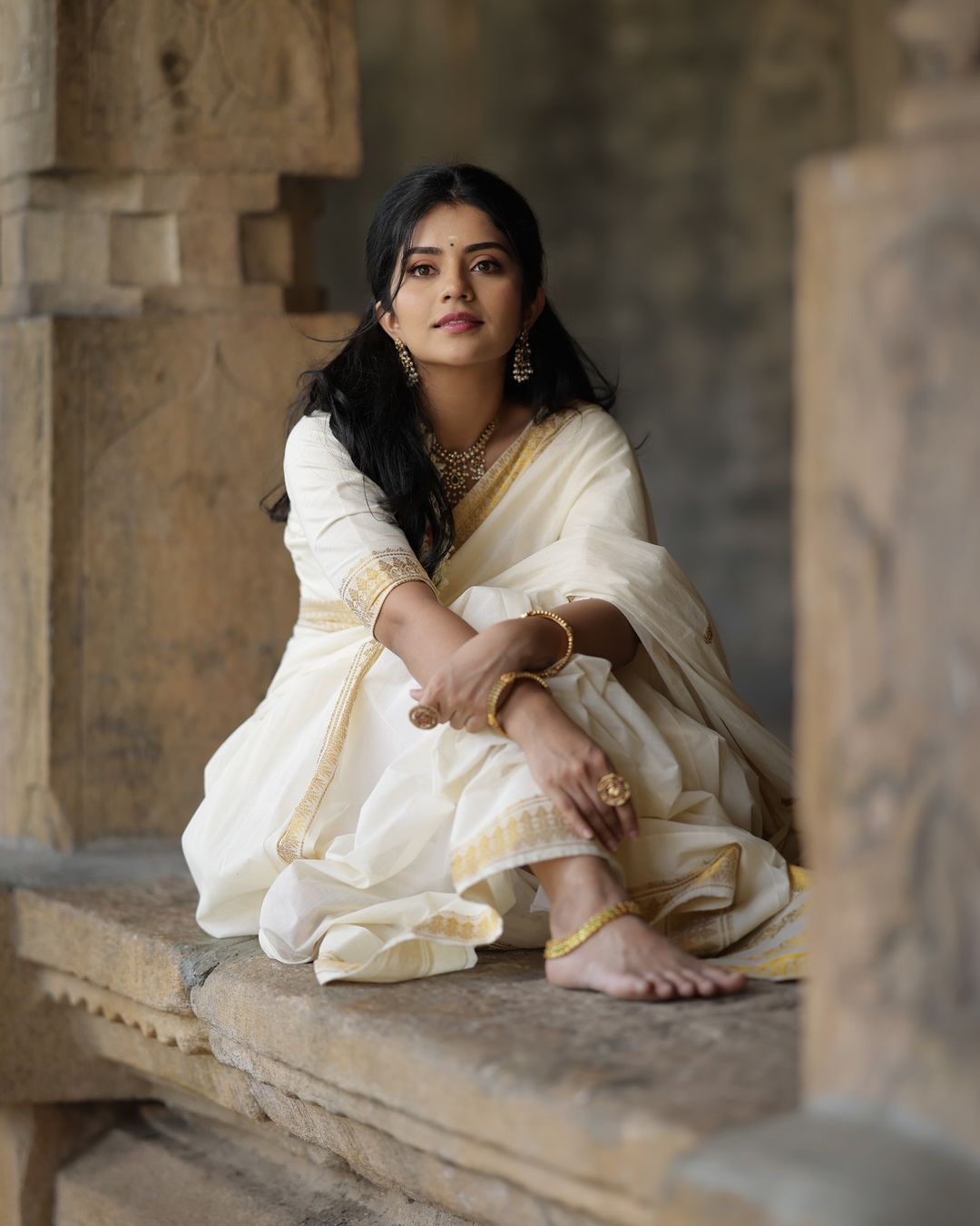 Megha Shetty is seen wearing a beautiful cream-colored saree with a gold border.