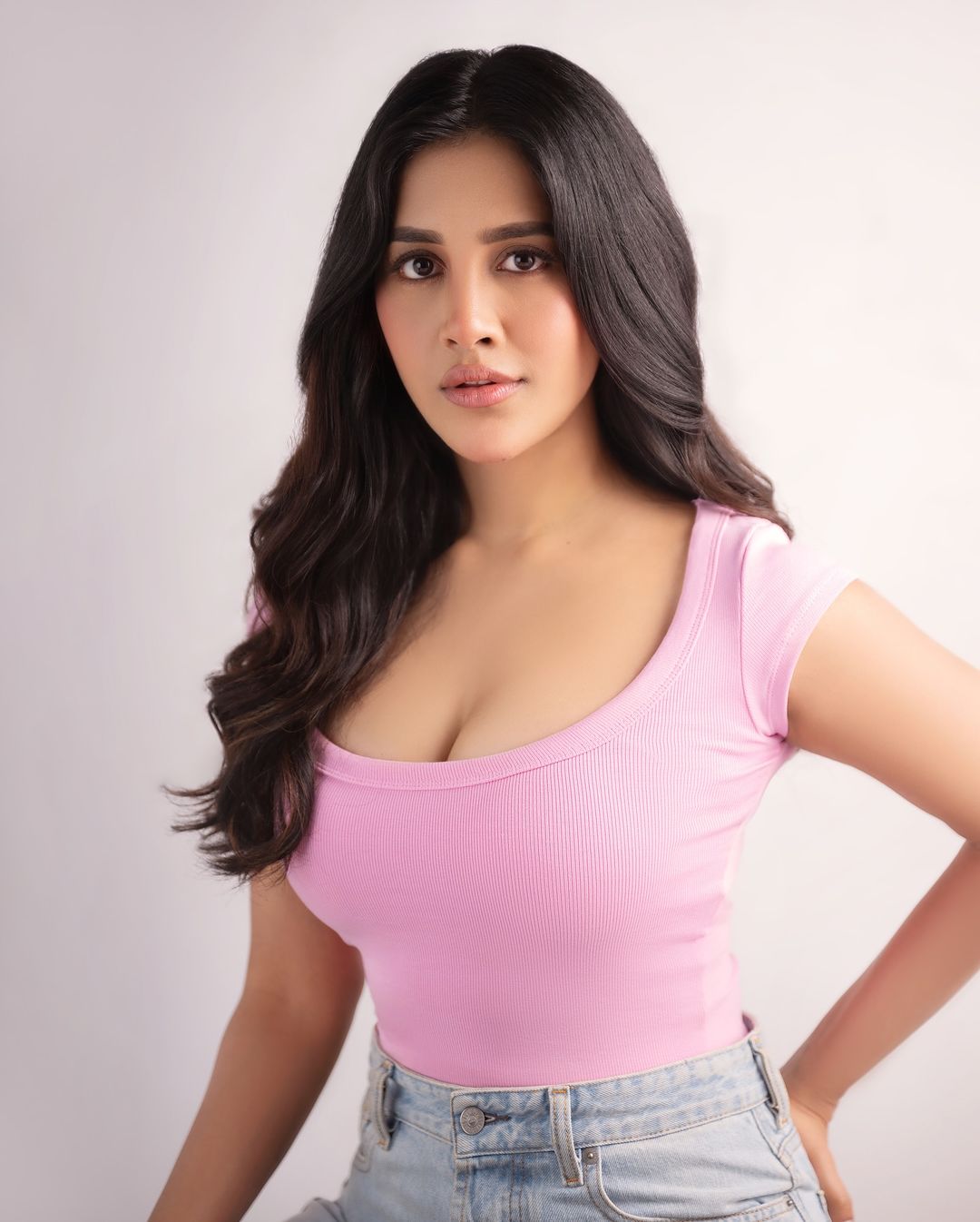 Nabha Natesh in her latest photoshoot, wearing a stylish pink top paired with blue jeans.