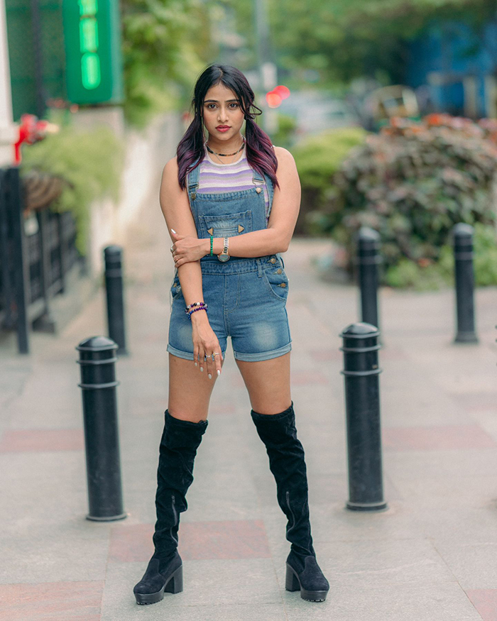 Kannada actress Sangeetha is wearing a denim dungaree over a pastel-colored, sleeveless top, which gives her outfit a youthful and casual look.