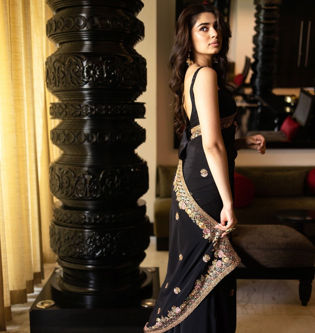 Krithi Shetty looks graceful in a black saree with intricate gold embroidery.