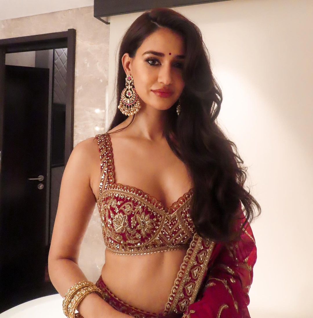 Disha Patani looks absolutely gorgeous in this maroon traditional wear. The lehenga complements her radiant beauty, and her poised demeanor adds to the overall elegance of the outfit.