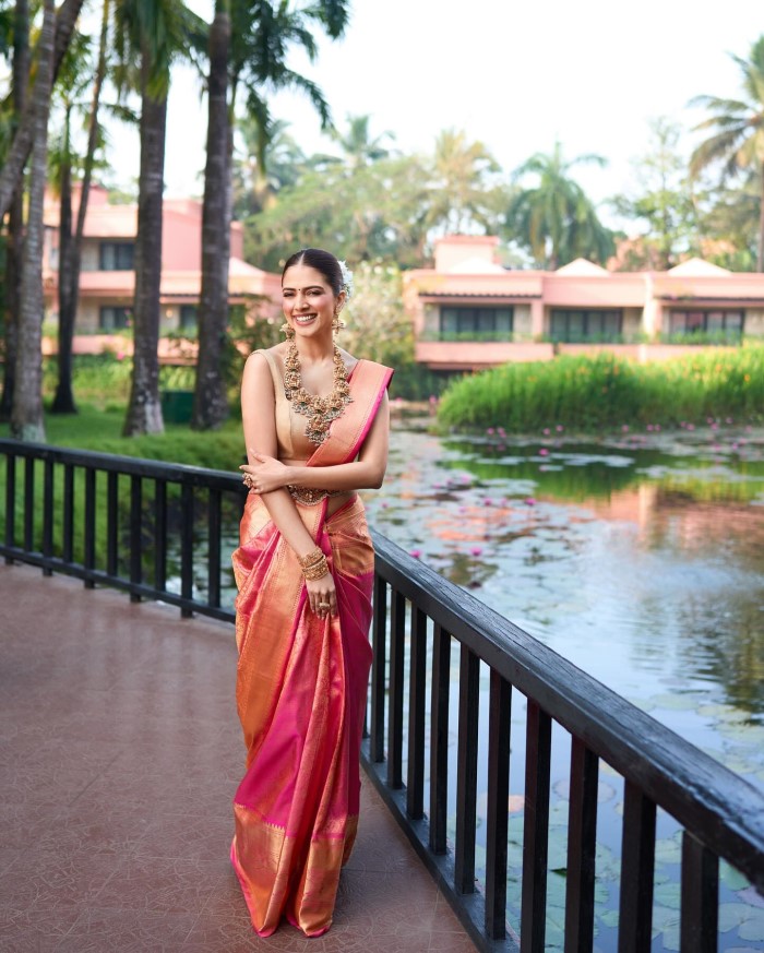 The saree is draped elegantly, enhancing her natural grace and poise, while the beautiful color and intricate patterns highlight the saree's cultural significance.