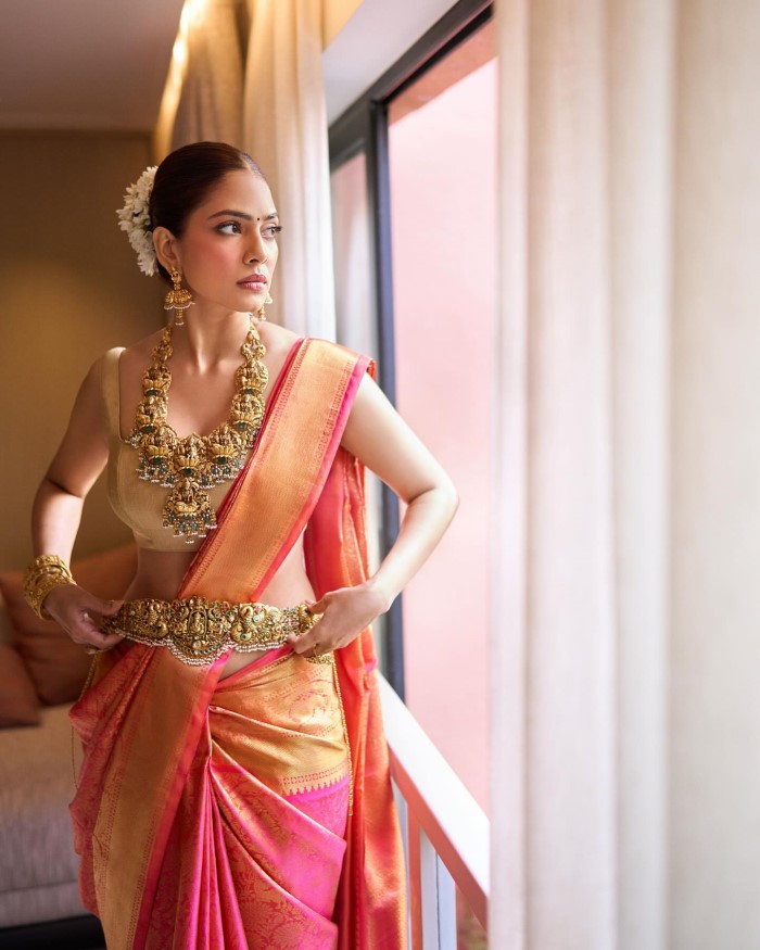 Malavika's makeup is kept minimal yet elegant, focusing on enhancing her natural beauty with a subtle, dewy finish, which perfectly complements her traditional attire.