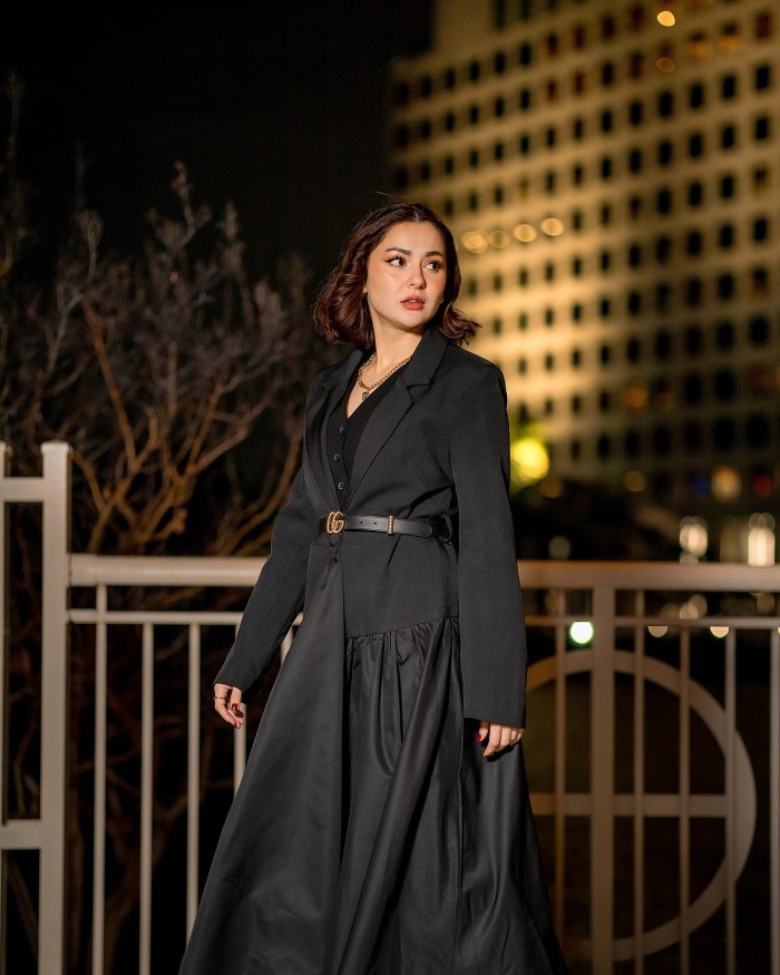 Hania Aamir stuns in a long black dress with long sleeves and a belted waist, showcasing her impeccable fashion sense.