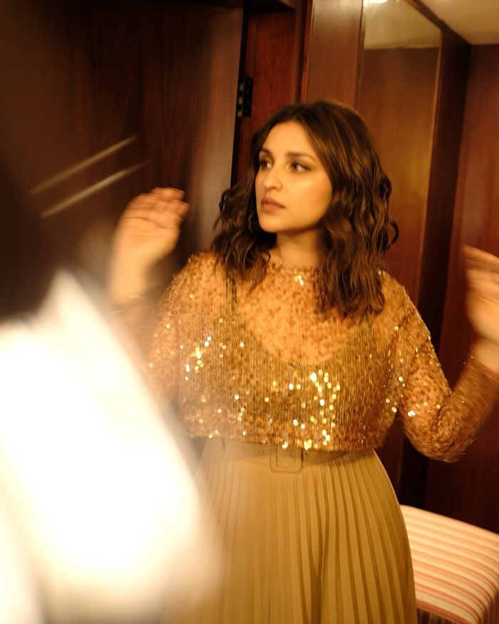 Parineeti Chopra wore a glamorous long-sleeved, sequined crop top in a golden-brown hue, adding a shimmering effect to her overall look.