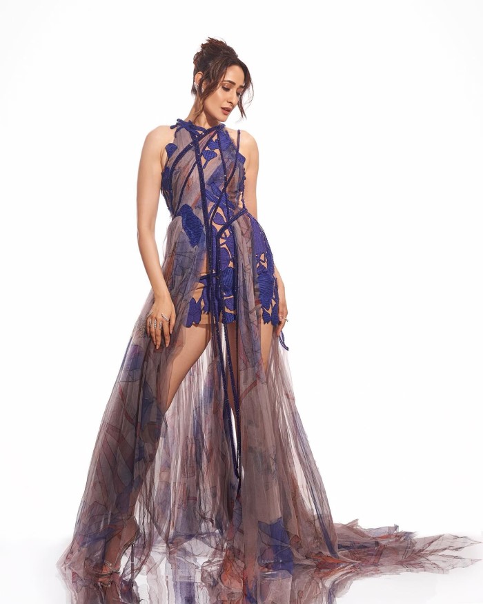 She completes the look with high-heeled sandals featuring thin straps, perfectly complementing her dress and adding to the overall sophisticated vibe.