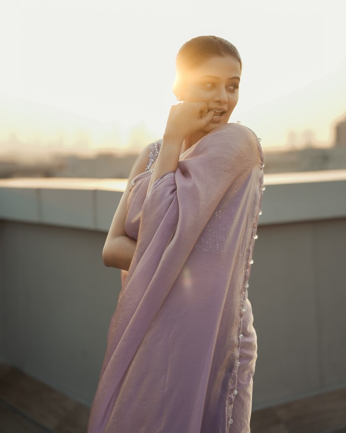 Her makeup is impeccably done, with a focus on subtle tones that accentuate her natural beauty. Her look is completed with a touch of classic elegance.