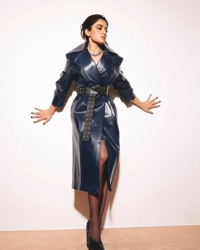 The cinched waist, emphasized by a studded black belt, adds definition and gives a modern, chic silhouette, perfect for high-fashion editorial shoots.