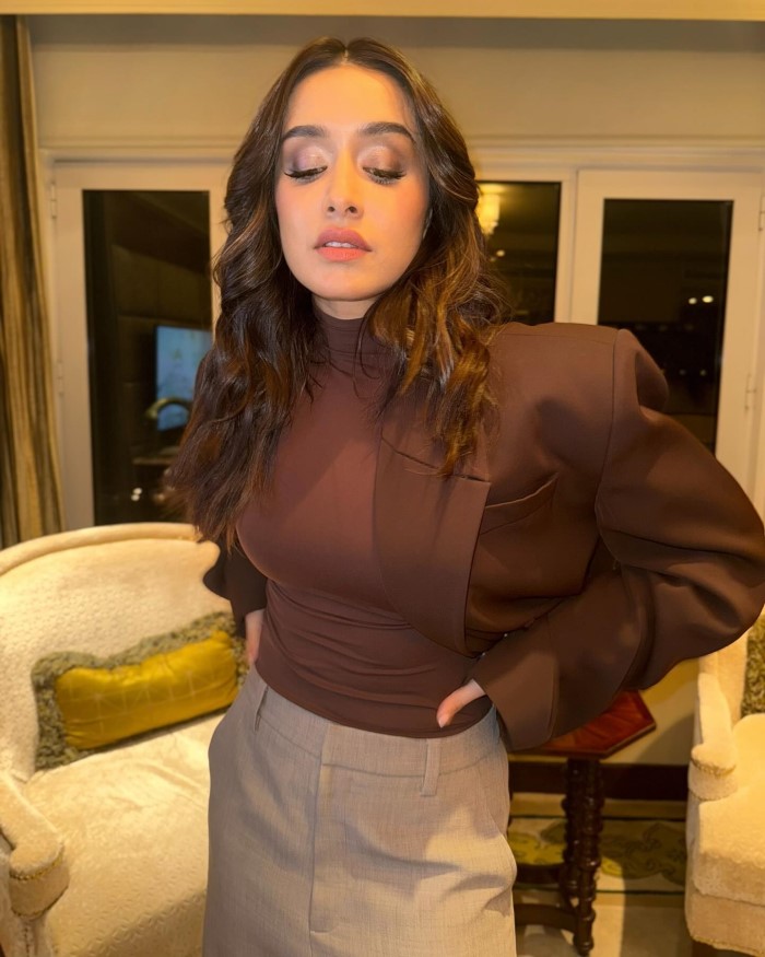 The beige wide-leg trousers add a neutral balance to the outfit, enhancing its overall sophistication.