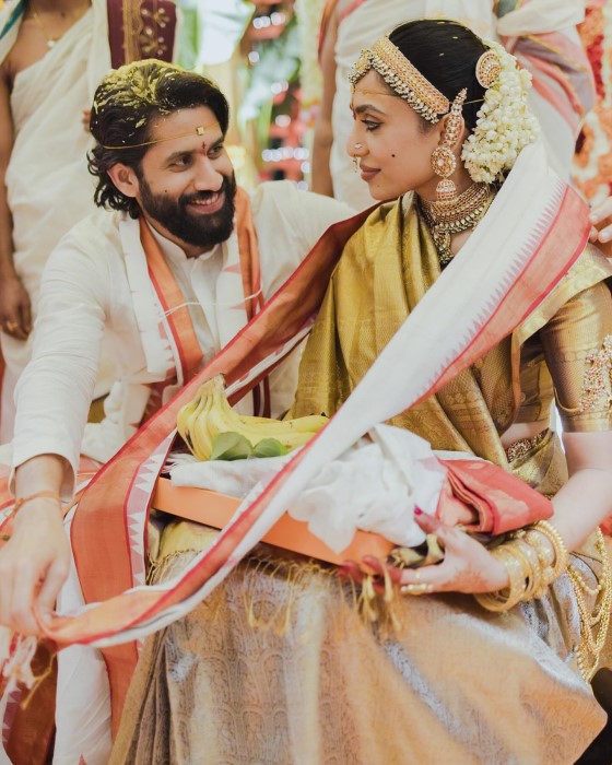 The couple looks breathtakingly beautiful in their South Indian bridal attire, with Sobhita in a white and red Kanchipuram saree and Naga Chaitanya in a golden-white kurta and veshti.