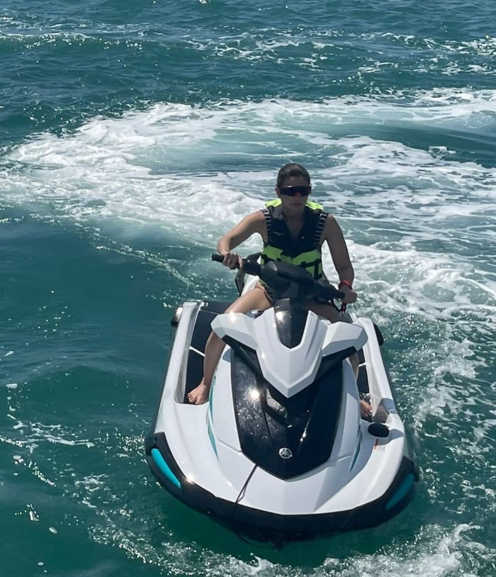 Alia Bhatt is having an adventurous moment as she rides a jet ski on the open water. Her life jacket ensures safety, while the choppy waves indicate she’s enjoying a thrilling ride.