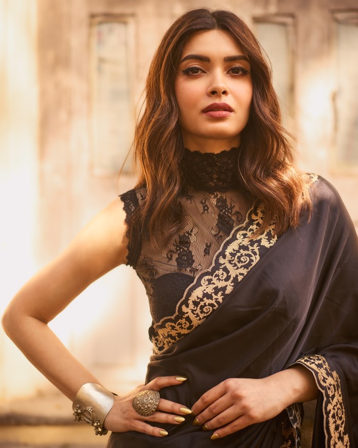 The gold nail polish and minimal makeup create a cohesive and stylish appearance, enhancing the intricate details of the saree and accessories.