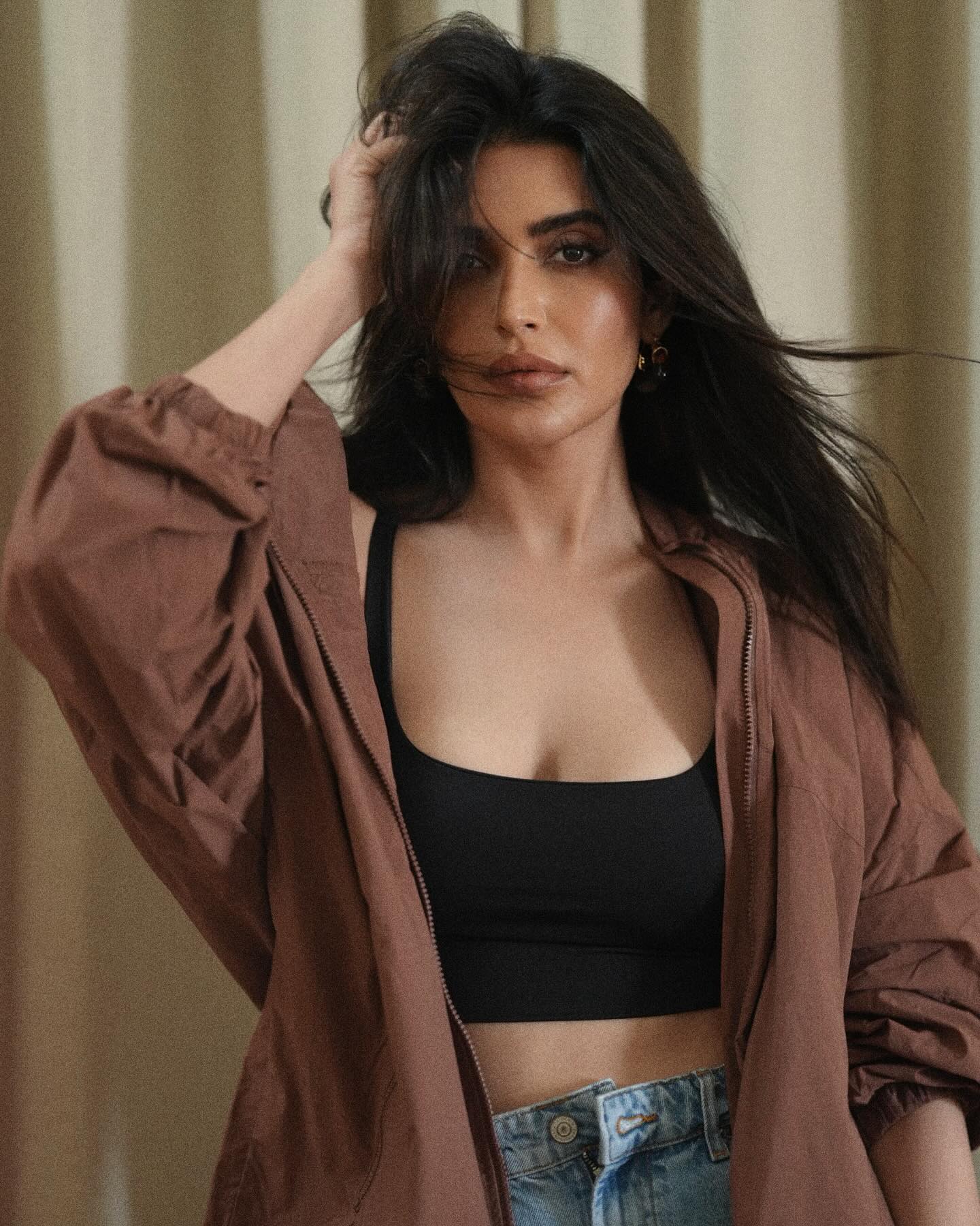 Karishma Tanna sports a relaxed yet stylish look, pairing a black crop top with high-waisted, distressed denim shorts.