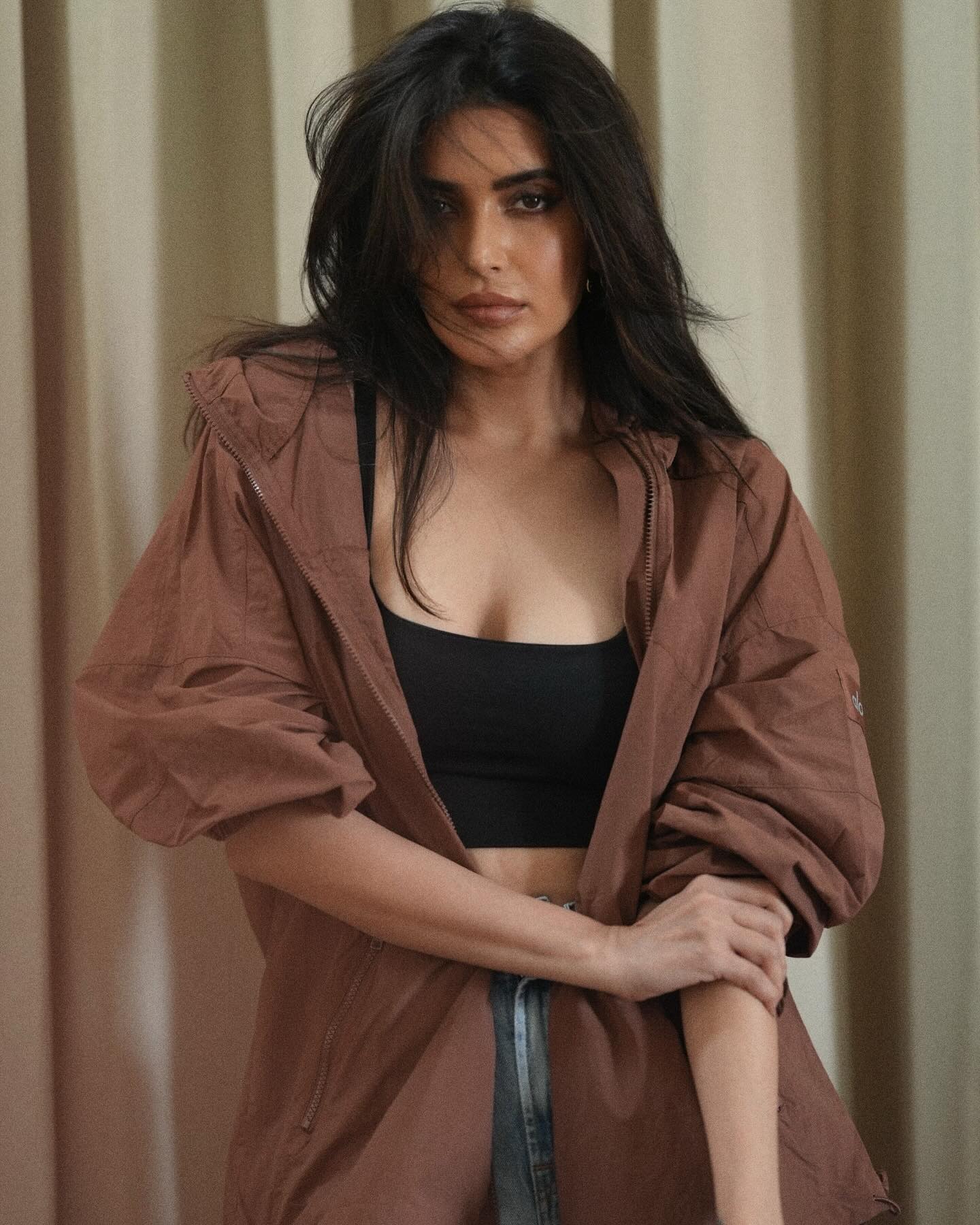 Karishma Tanna sports a relaxed yet stylish look, pairing a black crop top with high-waisted, distressed denim shorts.