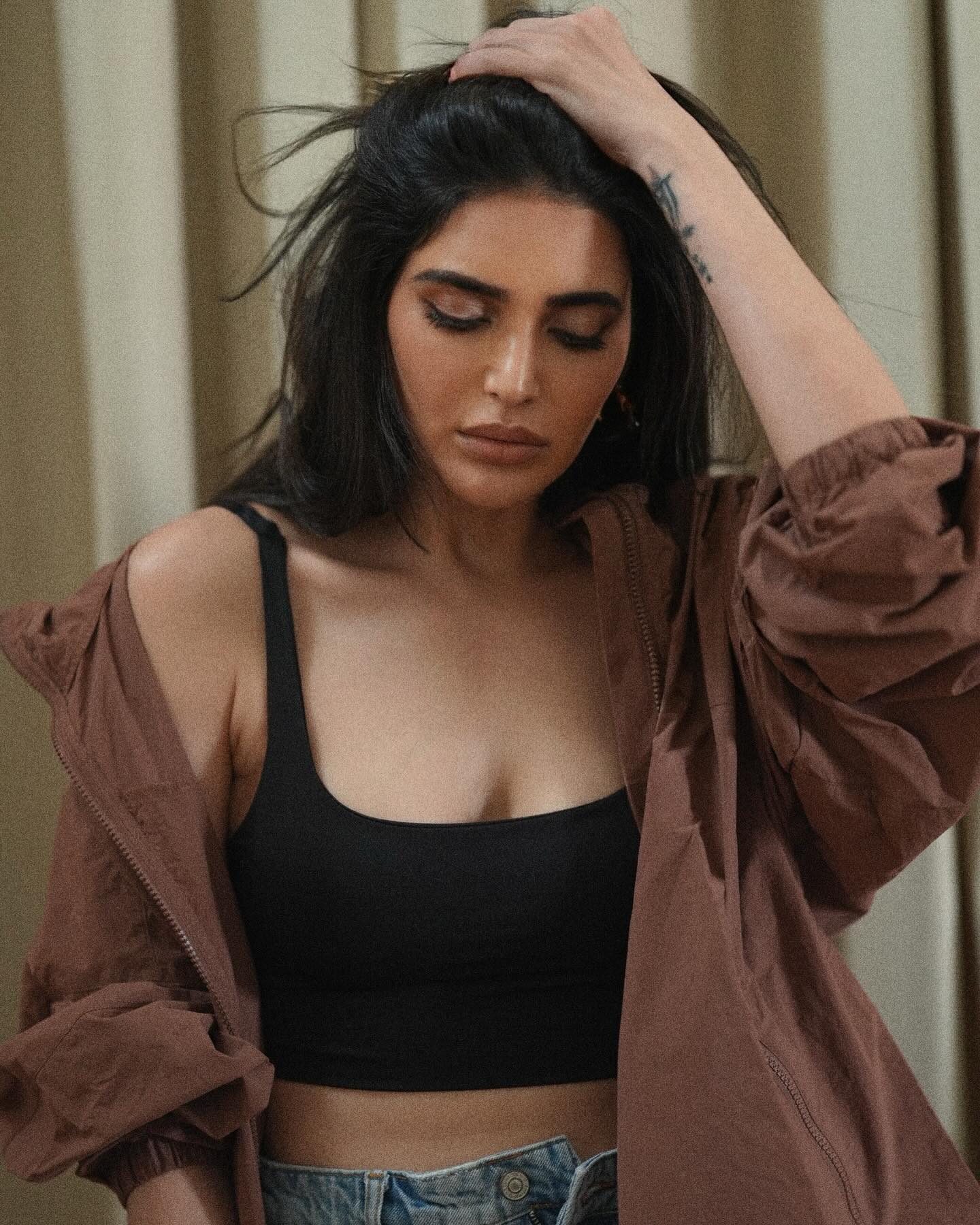 Karishma Tanna sports a relaxed yet stylish look, pairing a black crop top with high-waisted, distressed denim shorts.