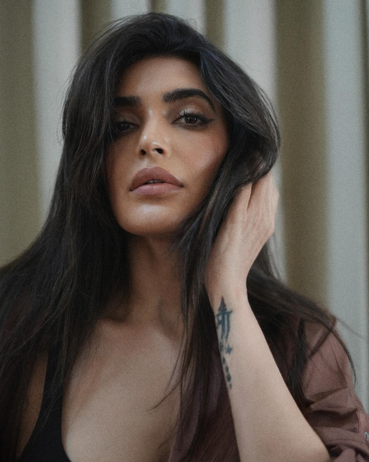 Karishma Tanna sports a relaxed yet stylish look, pairing a black crop top with high-waisted, distressed denim shorts.