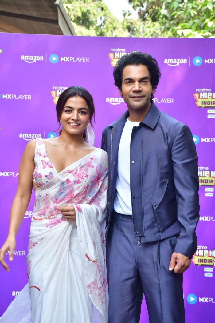 Rajkummar Rao looks dapper in a sleek blue suit paired with a white shirt, while Wamiqa Gabbi radiates elegance in a white saree adorned with delicate pink floral patterns.