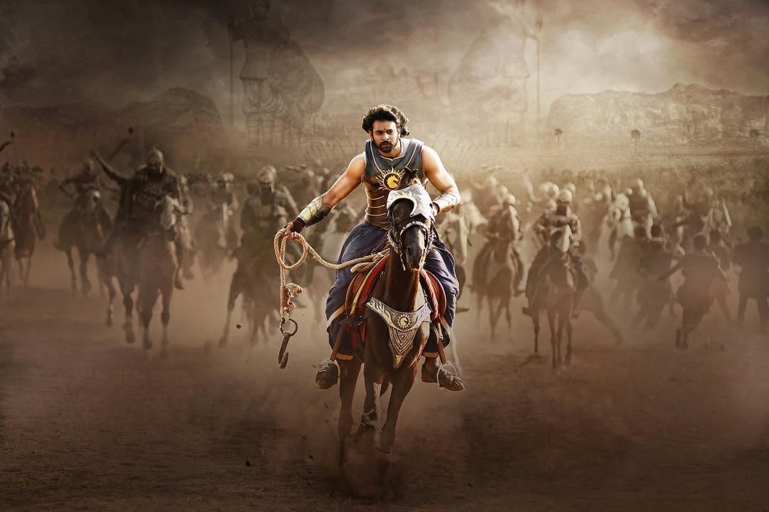 In Baahubali, Prabhas showcased two distinct looks—one as a fierce warrior and the other as a majestic king. As Amarendra Bahubali, he exuded royalty in rich armor, a regal crown, and a commanding presence. As Mahendra Bahubali, he embraced a rugged warrior avatar