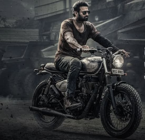 In Salaar, Prabhas sported a rugged and intense look, exuding raw power. He donned a rough, battle-hardened appearance with a thick beard, short hair, and dark, gritty outfits.