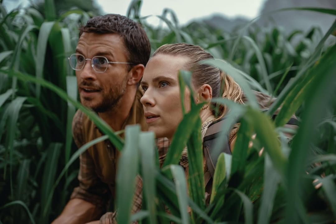 Movie still showing Scarlett Johansson and Jonathan Bailey mid-action during a dinosaur encounter