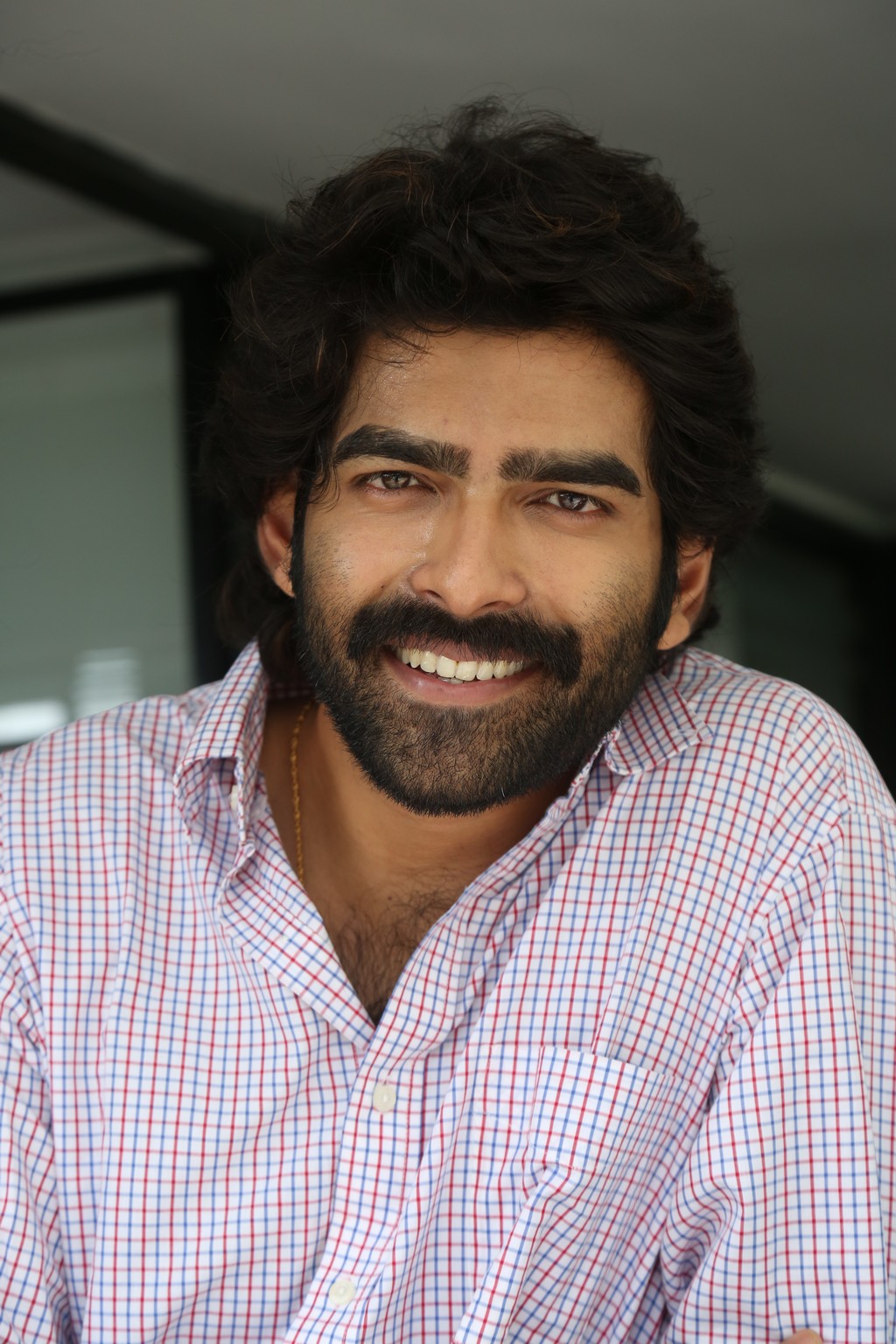 Manoj Chandra showcases how a winning smile and a smartly checked shirt can instantly light up any space–making professional charm look delightfully effortless.