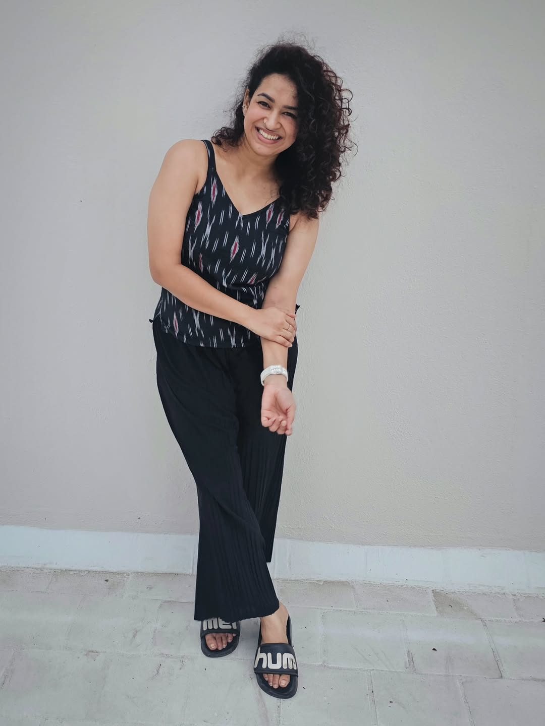 Meesha Ghoshal effortlessly combines style and humor – proving that a confident smile and a comfy pair of slides can make even a plain wall look runway-ready!