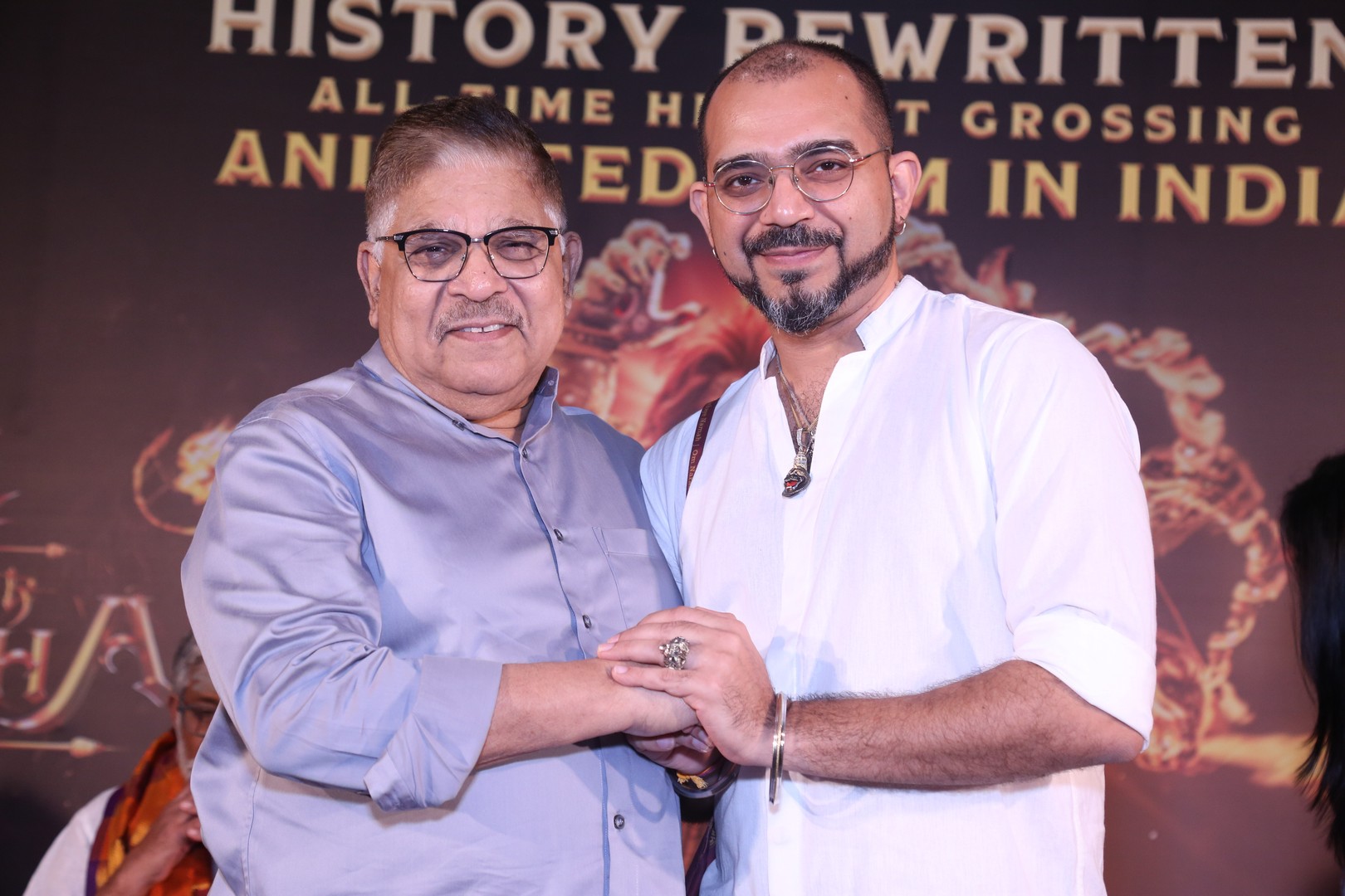 Allu Aravind and Ashwin Kumar seen warmly holding hands while posing for photographers, showcasing camaraderie.