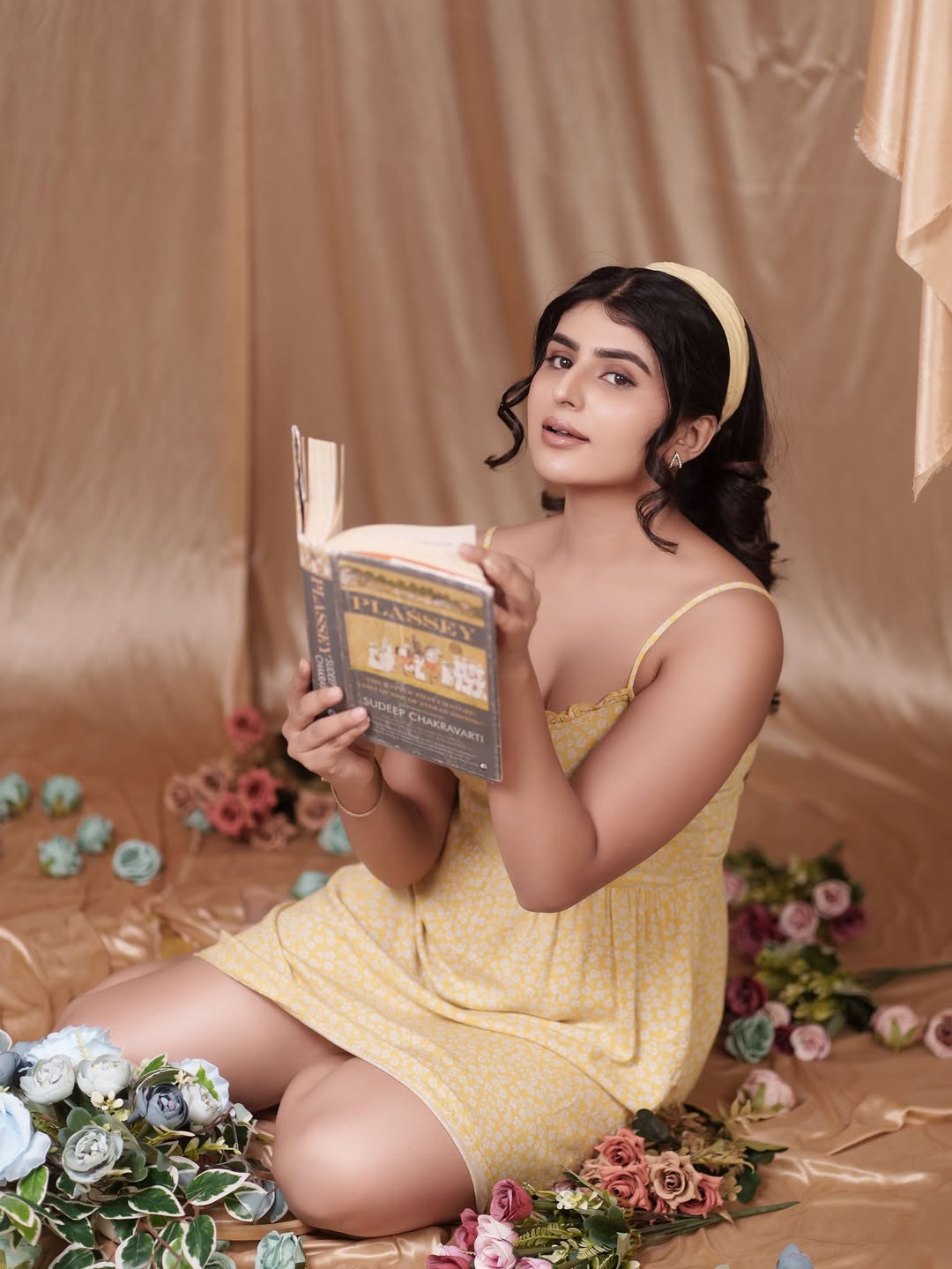 Sharanya Shetty exudes vintage charm in a sunny yellow dress, proving that even a book can look stylish when paired with a floral backdrop–proof that brains and beauty make the perfect bouquet!