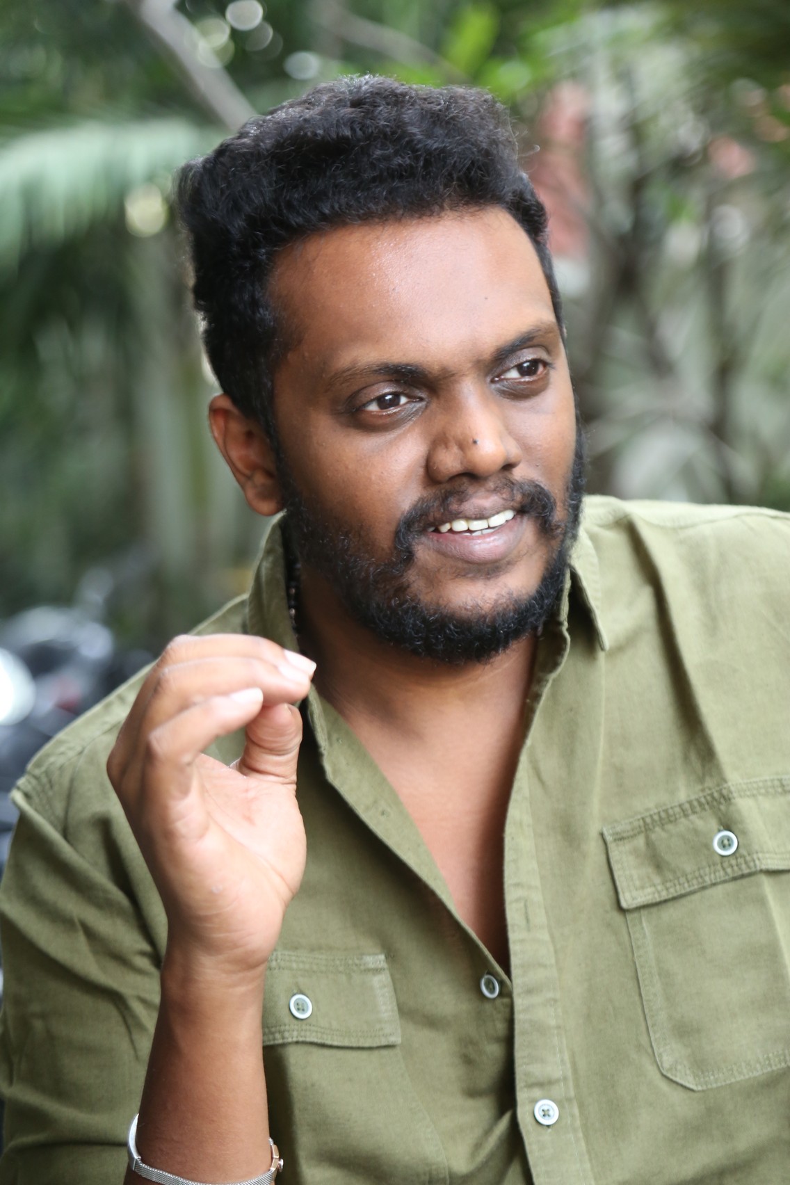 Sandeep Raj posing in polished casual outfit with green accents