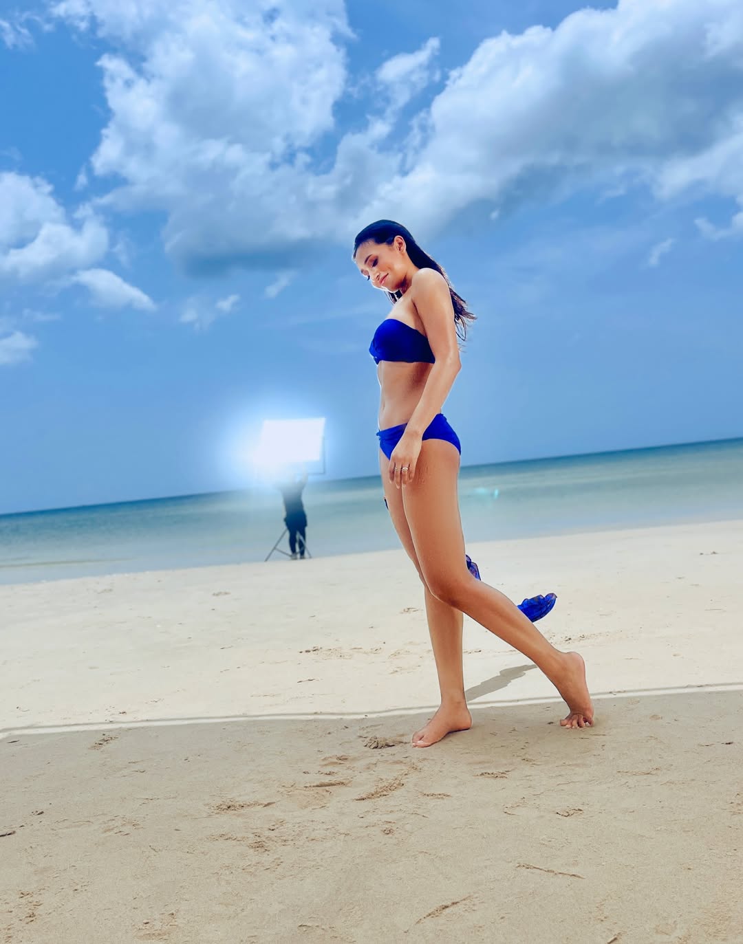 Mimi posing gracefully by ocean in blue outfit
