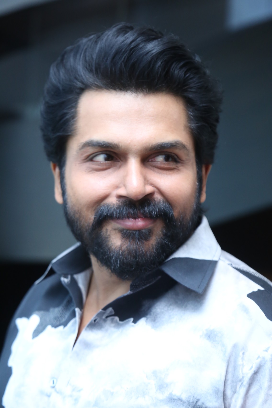 Karthi wearing stylish suit with playful confident charm