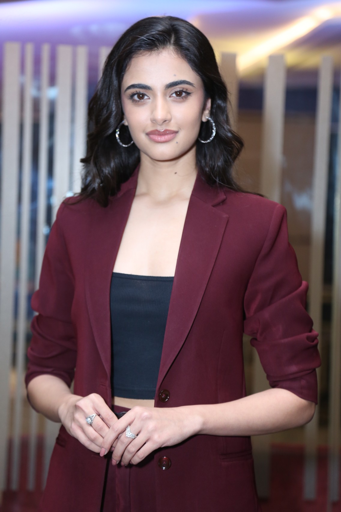 Rhea Singha in bold maroon blazer smiling confidently
