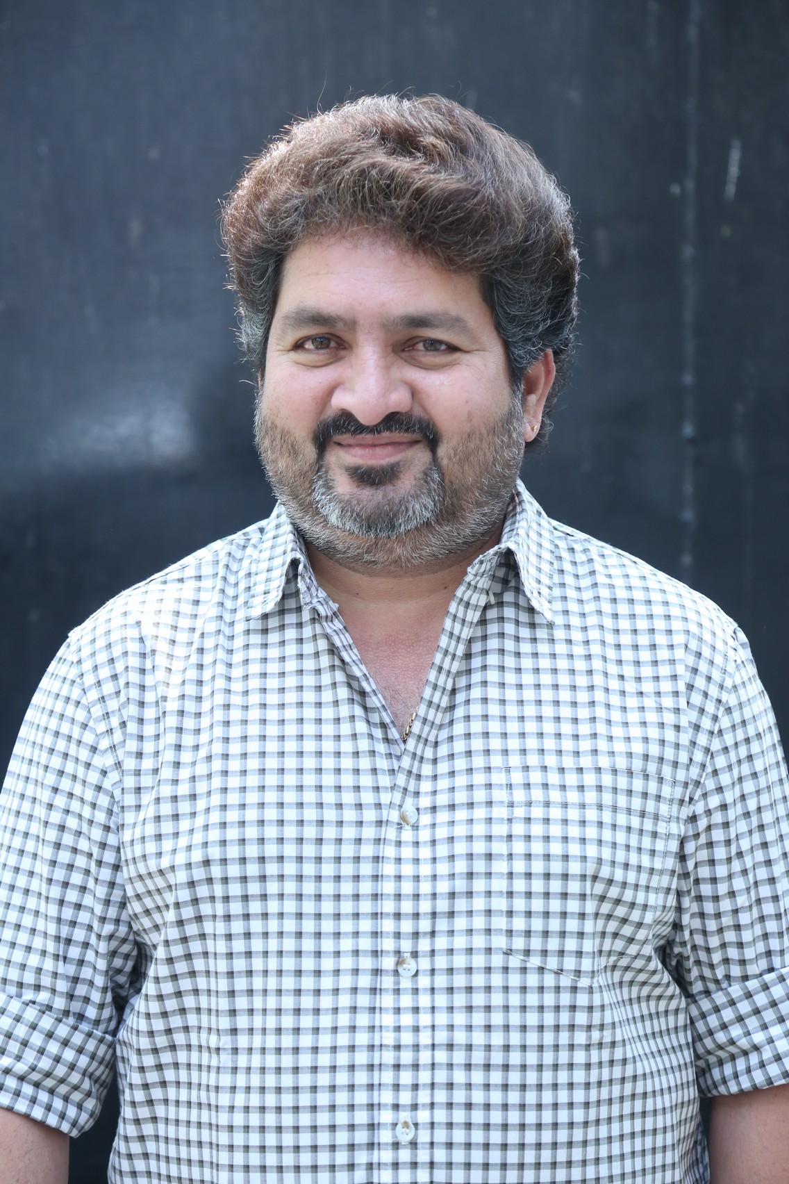 Kasarla Shyam smiling in casual checkered shirt