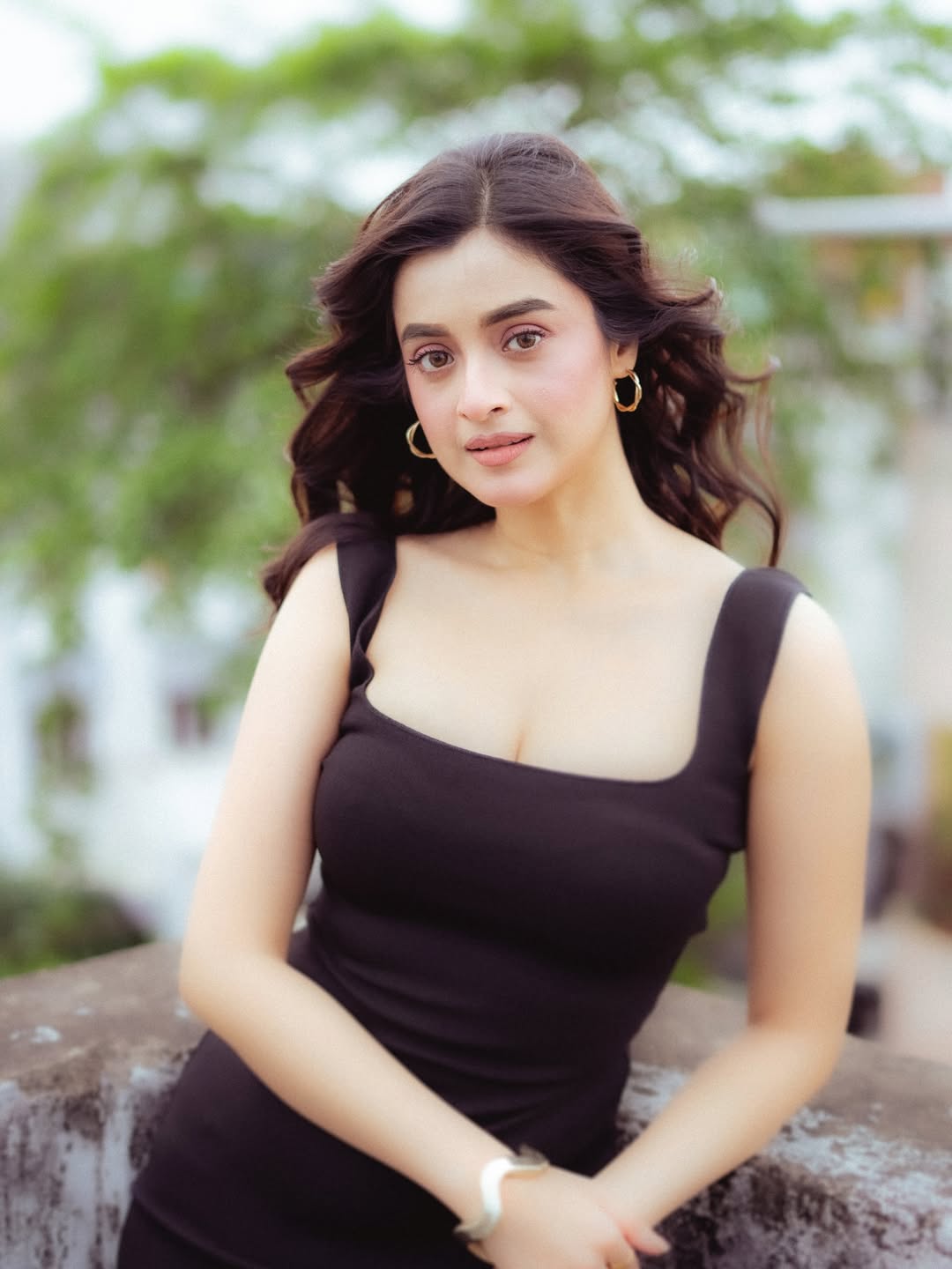 Darshana Banik in a classic little black dress with wind-swept hair on a rooftop