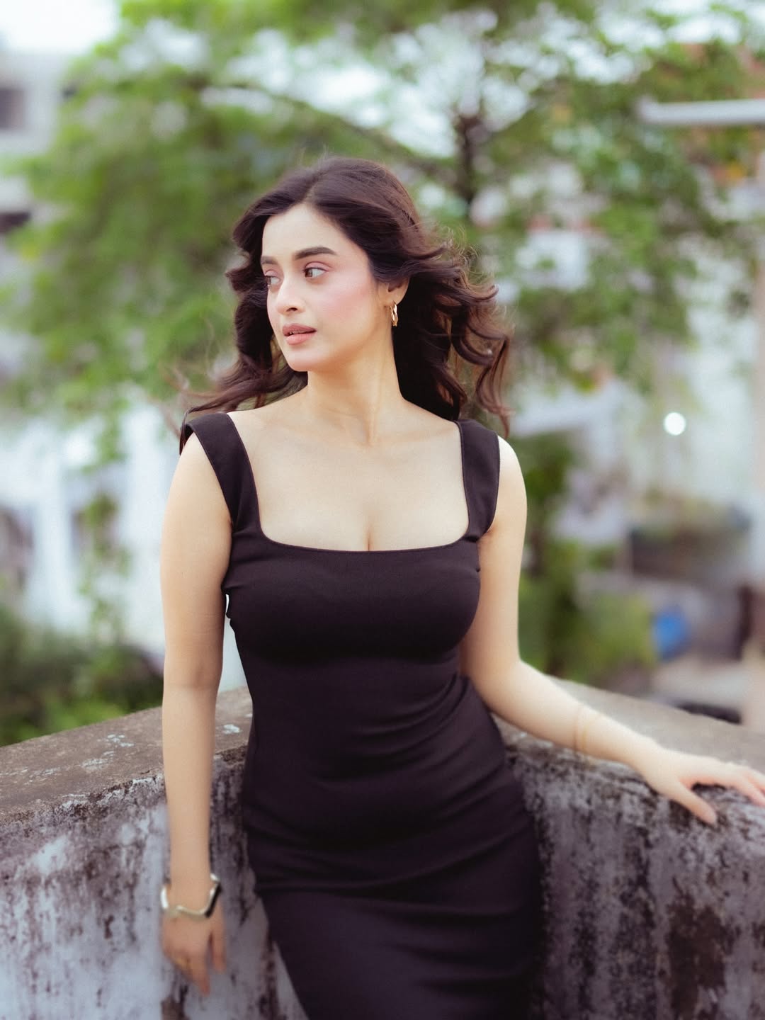 Darshana Banik posing on a rooftop in a black dress with breezy hair and cinematic vibe