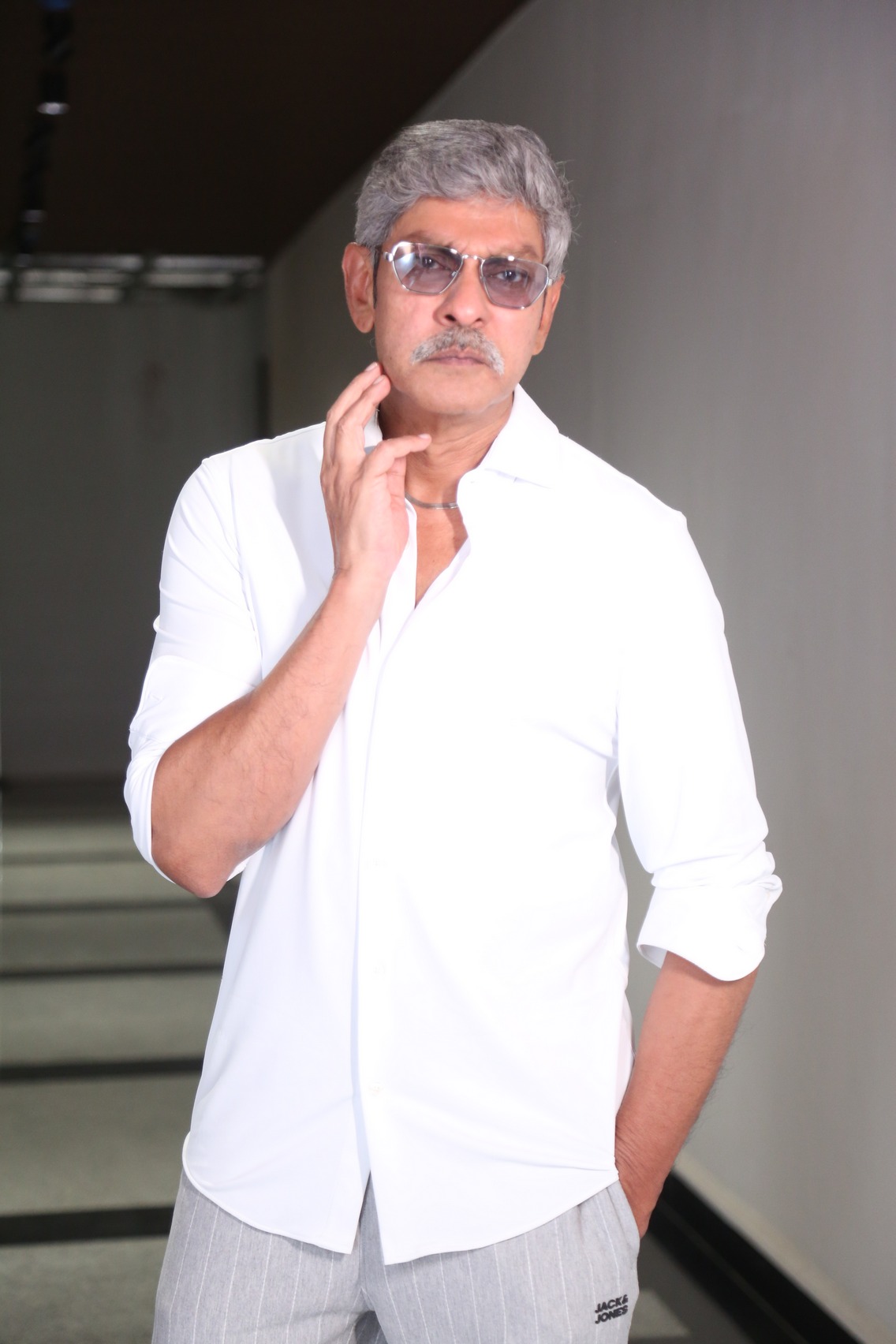 Jagapathi Babu in a white outfit posing confidently with a stylish demeanor