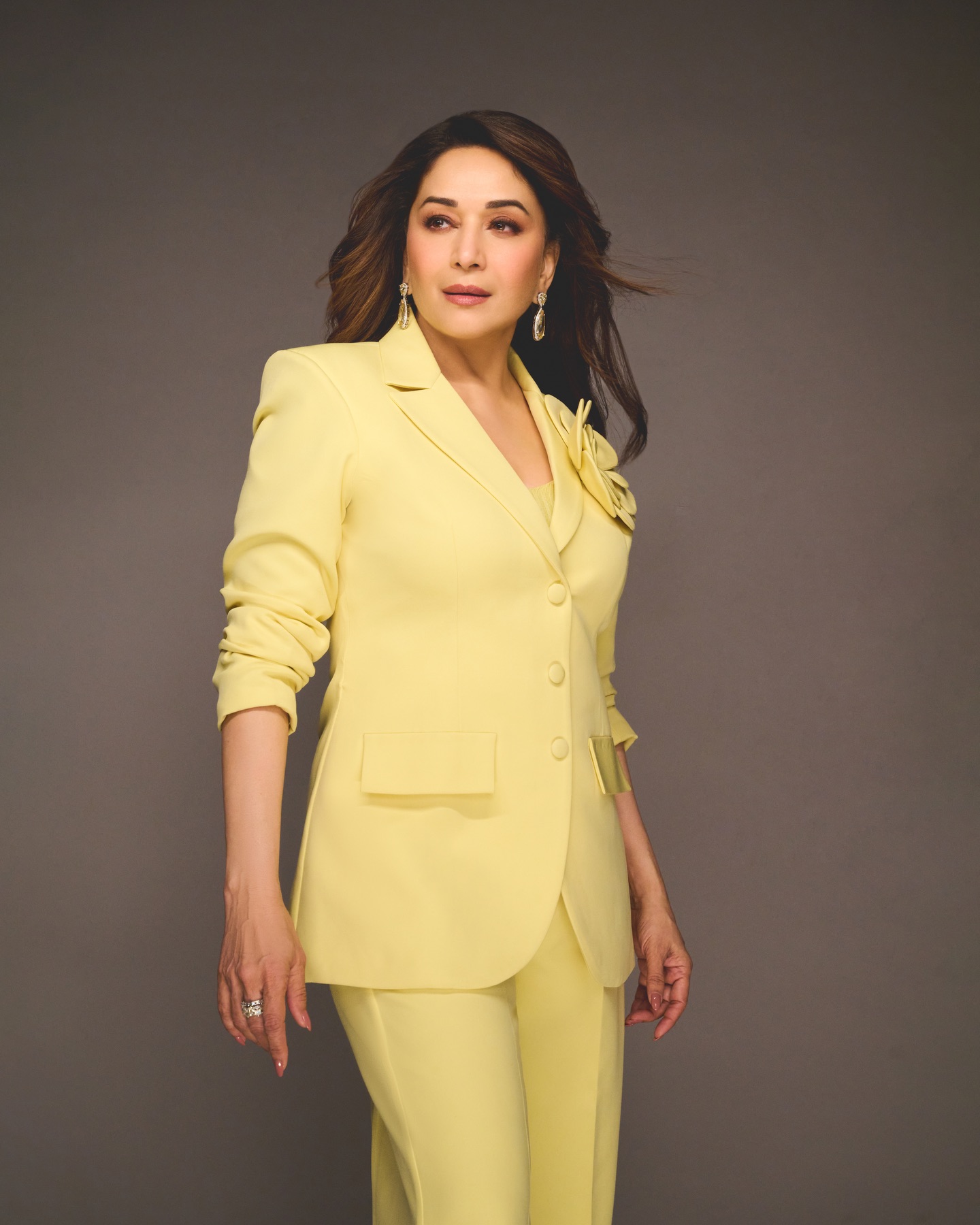 Madhuri Dixit showcasing confident pose in tailored yellow blazer and wide-leg trousers