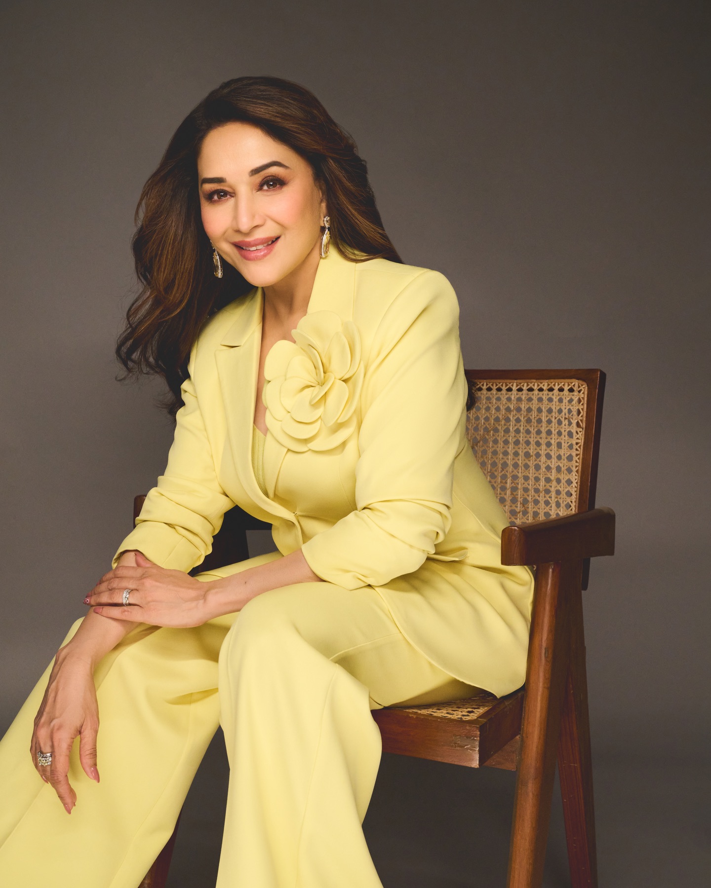Madhuri Dixit wearing bold yellow suit with floral embellishment on shoulder