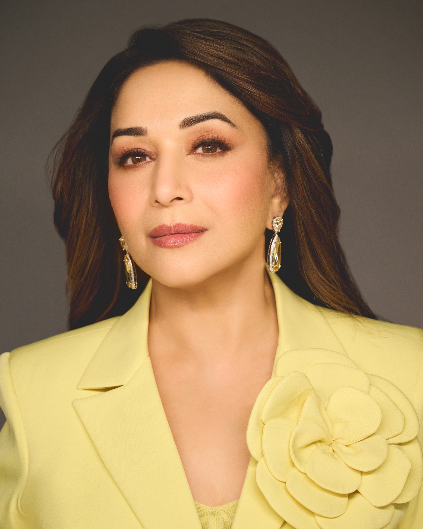 Madhuri Dixit posing with hand-on-waist stance in structured yellow blazer
