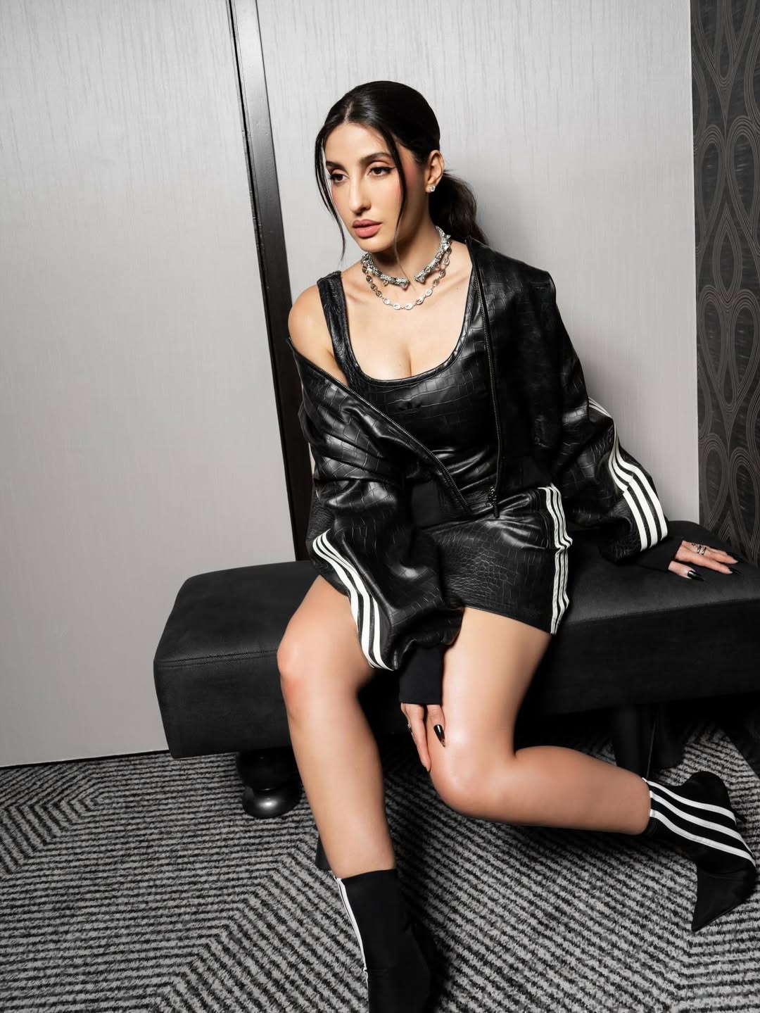 Nora Fatehi black outfit leather stripes chic pose