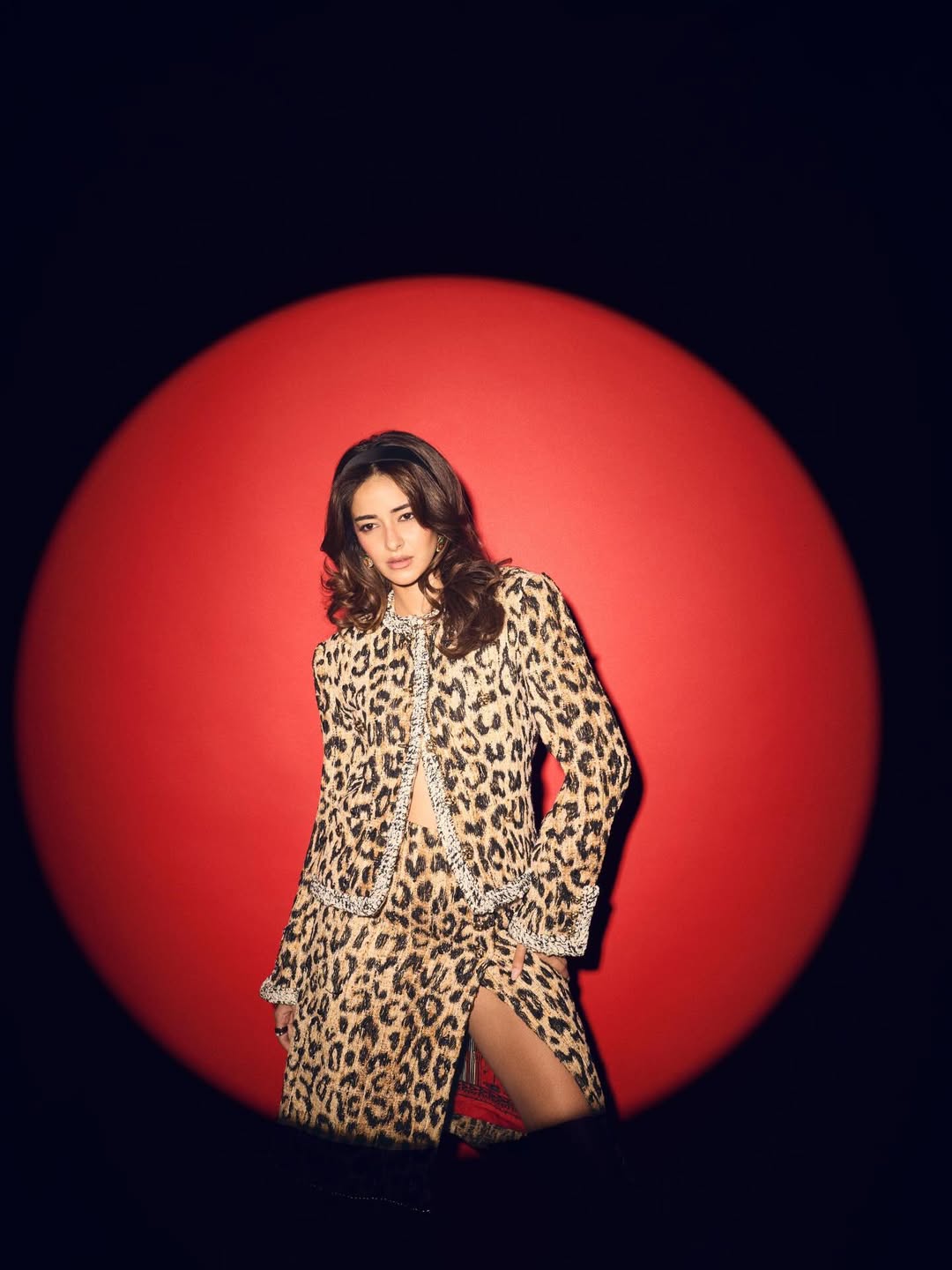 Ananya Panday posing in a bold leopard-print jacket and slit skirt with glamorous styling.