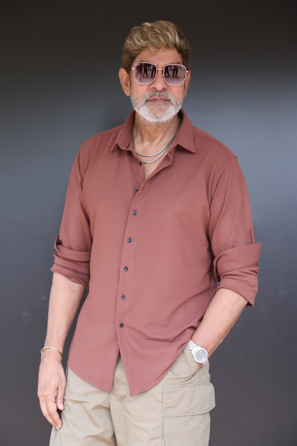 Jagapathi Babu in dusty rose shirt stylishly posing.